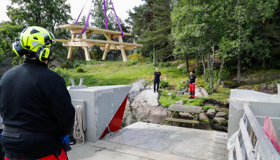 KRANFØRER: Steinar Andreassen løfter et nytt bord som skal ut på øya inn på tørr grunn. KRANFØRER: Steinar Andreassen løfter et nytt bord som skal ut på øya inn på tørr grunn.
