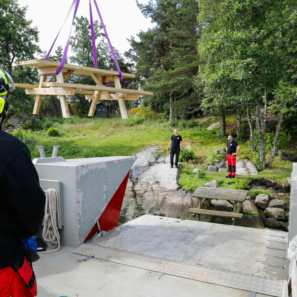 KRANFØRER: Steinar Andreassen løfter et nytt bord som skal ut på øya inn på tørr grunn. KRANFØRER: Steinar Andreassen løfter et nytt bord som skal ut på øya inn på tørr grunn.