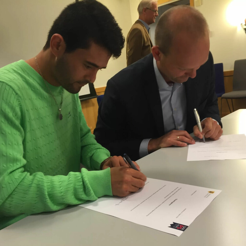 NAJIBOLLAH RAHINI: Signerer kontrakt med ordfører Sindre Martinsen Evje. NAJIBOLLAH RAHINI: Signerer kontrakt med ordfører Sindre Martinsen Evje.