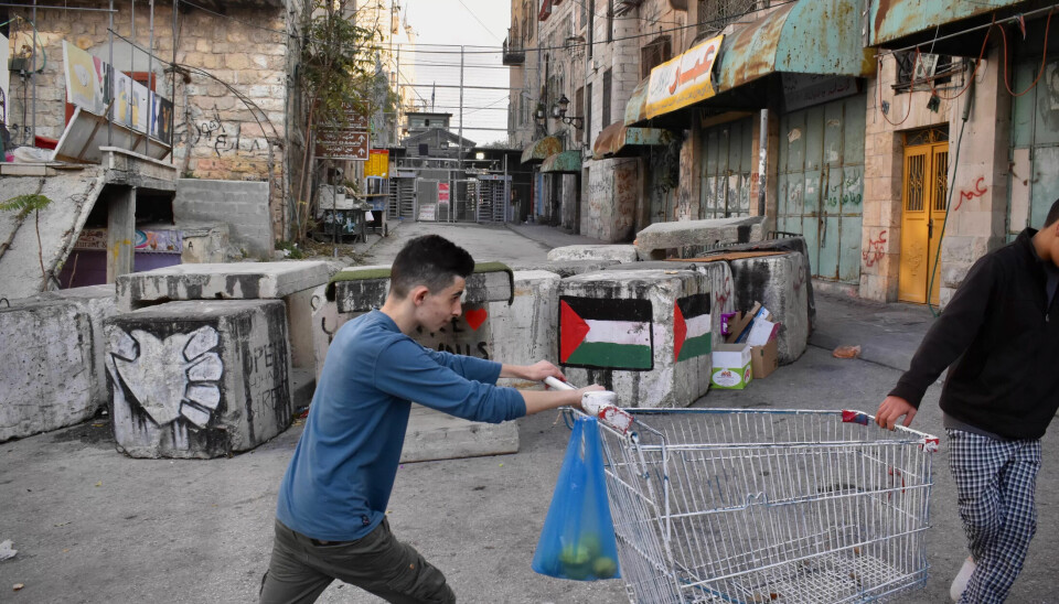 Palestinske ungdommer ved den en gang så livlige hovedgata Al-Shuhada-gata (Martyr-gata). I 2010 ble de palestinske butikkene stengt, og den militære kontrollposten stopper palestinere flest. Palestinske ungdommer ved den en gang så livlige hovedgata Al-Shuhada-gata (Martyr-gata). I 2010 ble de palestinske butikkene stengt, og den militære kontrollposten stopper palestinere flest.